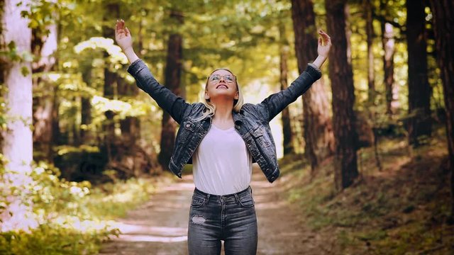 Young Blond Woman Enjoying The Nature, Outstretched Arms While Enjoying The Fresh Air In Green Forest