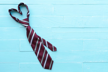 Happy fathers day concept. Red tie in heart shape on bright blue pastel wooden table background.
