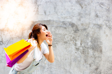 Portrait charming beautiful shopping woman. Attractive beautiful woman is telling, yelling to copy space that some brand, product, goods or service have discounted. Lovely girl hold shopping bags.