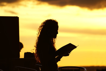 Beautiful redhead reading a book at sunset