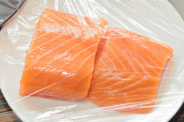 steaks of raw salmon in polyethylene on a white plate
