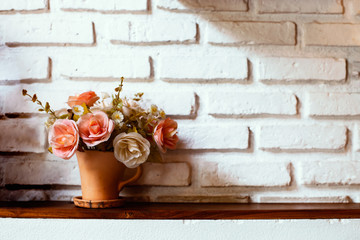 Beautiful flowers in vase on brick wall background in vintage color tone