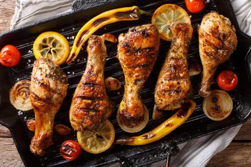 Foto op Plexiglas anti-reflex Delicious food: grilled chicken drumstick legs with vegetables in a grill pan close-up on a table. horizontal top view, rustic © FomaA