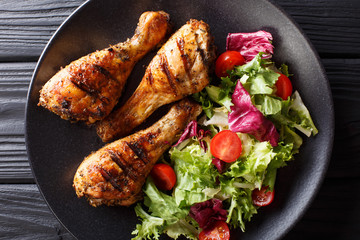 Crispy grilled chicken legs and fresh vegetable salad close-up. horizontal top view