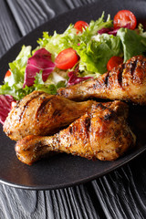 Crispy grilled chicken legs and fresh vegetable salad close-up. vertical