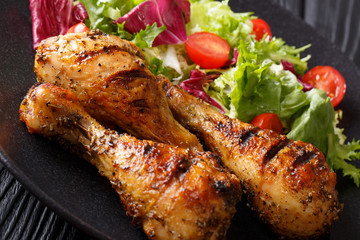Hot grilled chicken legs and fresh salad close-up on a plate. horizontal
