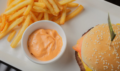 Burger on a plate with fried potatoes and sauce