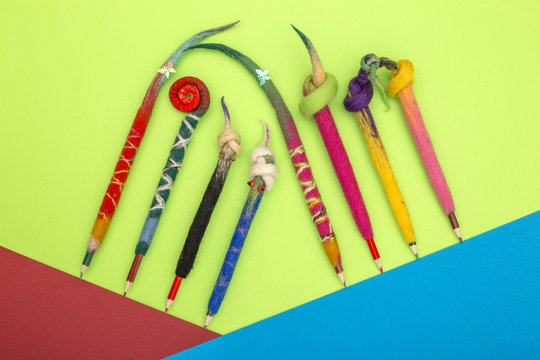 Pencils in a cover of fulled wool on a colour background
