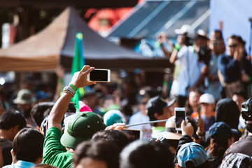 Young man taking photo of events using mobile phone - Powered by Adobe