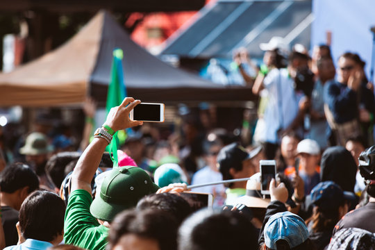 Young man taking photo of events using mobile phone