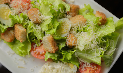 Caesar salad on a white plate and a glass background