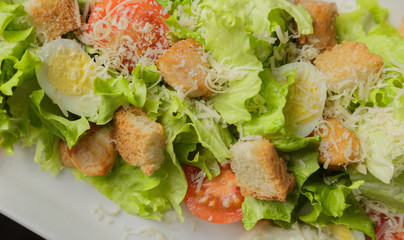 Caesar salad on a white plate and a glass background