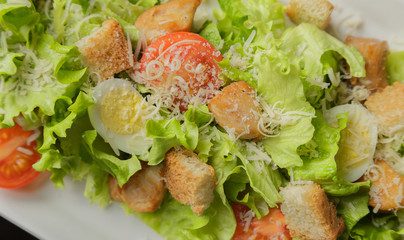 Caesar salad on a white plate and a glass background