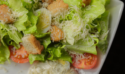 Caesar salad on a white plate and a glass background