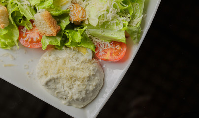 Caesar salad on a white plate and a glass background