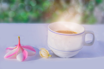 Abstract soft blurred and soft focus a cup of coffee with the Plumeria, Frangipani, Michelia alba, Magnolia, flowers, the bokeh, beam light, lens flare effect tone background.
