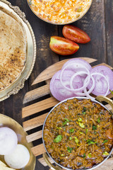 Indian Cuisine Sev Tamatar Also Called Sev Tamaeta or Sev Tameta is Served With Chapati, Papad, Onion or Raita. It is Made With Tomato And Onion Gravy With a Twist of Spicy Sev on Wooden Table
