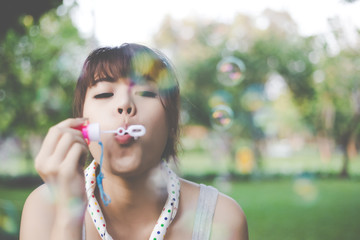 Charming beautiful woman is blowing soap bubbles to air. Gorgeous beautiful girl stay at park....