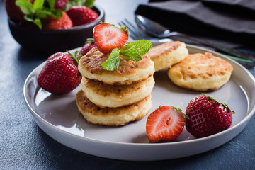 Cottage cheese pancakes with strawberry on blue concrete table background. Breakfast or Lunch Concept. Close-up