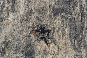 The the speleologist girl in mountaineering equipment passes a site of a route on trolley