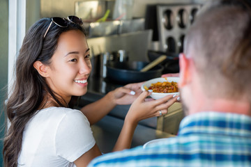 Happy young Asian woman getting pasta from food truck