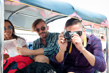 Group of tourist friends enjoying  traveling on local Tuk Tuk taxi exploring  Bangkok city Thailand