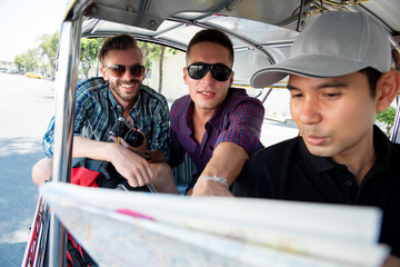 Tourists talking with driver asking for location while traveling by local Tuk Tuk taxi in Bangkok Thailand
