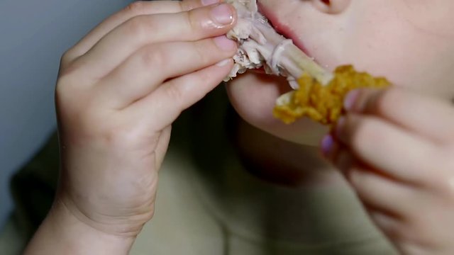 close up shot of a teenager's mouth, a child starving to eat poultry meat, which holds in his hands