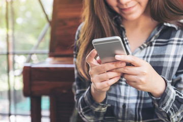 Closeup image of a woman holding , using and looking at smart phone