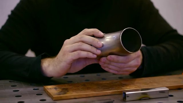 close up shot of a man's hands, who holds in hand a finished aluminum part
