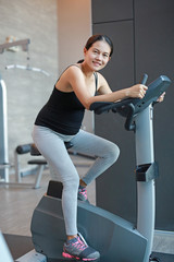 Pregnant woman exercise on the bicycle in sports hall.