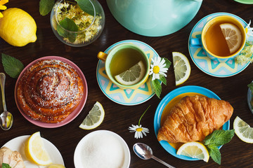 Cups with green tea, lemon and baked goods on the wooden background