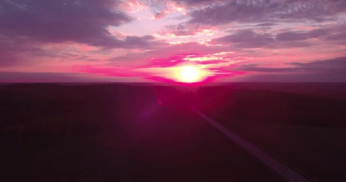Areial view of a long straight road and a colorful sky at sunset. 4K