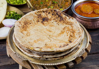 Indian Cuisine Chapati Also Called Roti, Flatbread, Chapathi or Chapatti Served With Sev Tamatar, Gatta Curry, Raita, Papad or Onion on Wooden Background