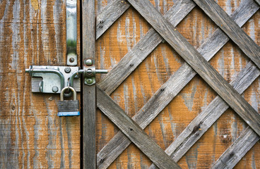 The wooden door with the hammered laths is closed on the padlock