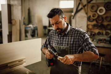 handsome joiner work in carpentry. He is successful entrepreneur at his workplace.