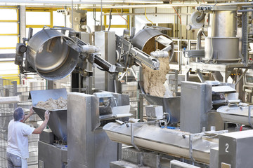 Arbeiter bedient Knetmaschinen in einer Großbäckerei - industrielle Herstellung am Fliessband von...