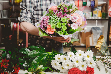 Modern bouquet of roses in rustic style, chrysanthemums, florist man holding flowers