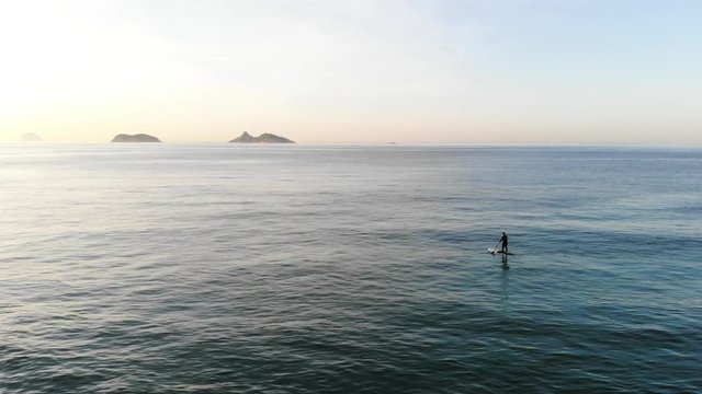 Drone footage of beach at sunrise with stand up padle riding at sea.