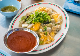 Fried oysters with eeg thai food with spicy sauce on dish.