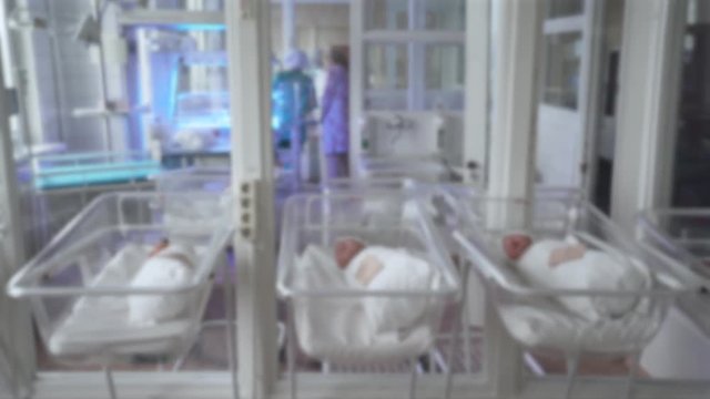 Blurred view of interior maternity hospital, newborn babies in cots.
