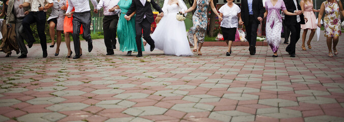 Newlyweds and guests of the wedding walking along the park together