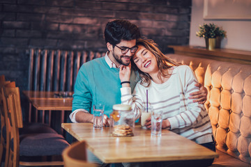  Beautiful loving couple sitting in a cafe drinking coffee and conversating. Love and romance concept.