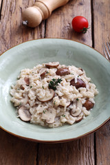 risotto con funghi tradizionale italiano su sfondo tavolo di cucina rustico