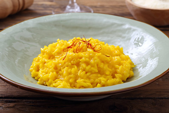 risotto allo zafferano tradizionale italiano su sfondo tavolo di cucina rustico