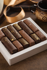 Handmade bonbons with gold splashes in box on wooden background