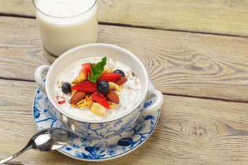 Bowl of homemade granola with yogurt and fresh berries on wooden background