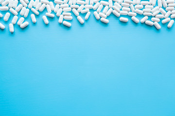 White pills on the blue table. Mock up for special offers as advertising, web background or other ideas. Medical, pharmacy and healthcare concept. Copy space. Empty place for text or logo.
