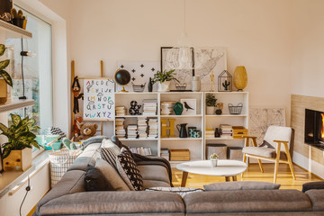 Sun coming through a large window into a cozy, scandinavian living room interior with a bio...