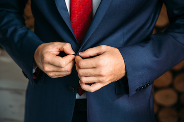 Close-up businessman groom wearing his jacket at the morning of wedding day. Concept of men stylish elegance clothes.